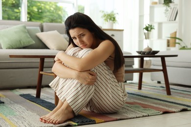 Photo of Emotional woman suffering from panic on floor indoors
