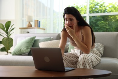 Photo of Emotional woman suffering from panic near laptop indoors