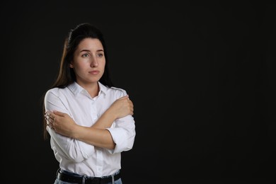 Photo of Panic attack. Woman calming herself down on black background, space for text