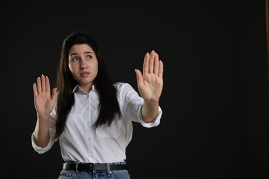 Photo of Woman suffering from panic attack on black background, space for text