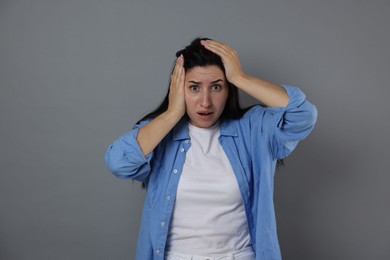 Photo of Woman suffering from panic attack on grey background