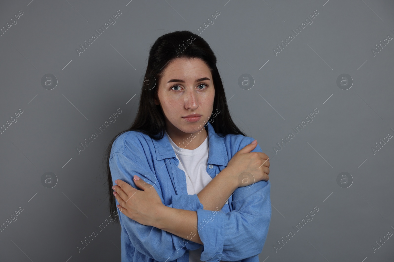 Panic attack. Woman calming herself down on grey background Photo of Panic attack. Woman calming herself down on grey background