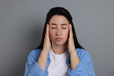 Photo of Panic attack. Woman calming herself down on grey background