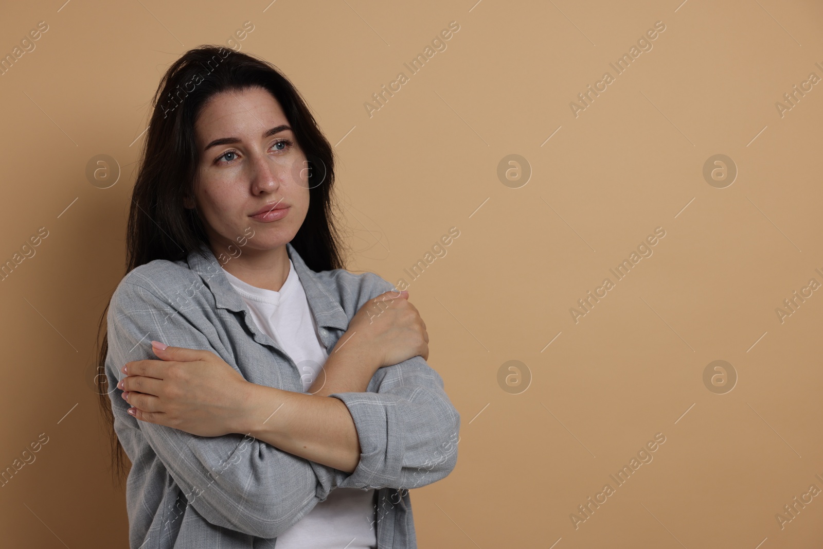 Photo of Panic attack. Woman calming herself down on beige background, space for text