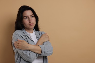 Photo of Panic attack. Woman calming herself down on beige background, space for text