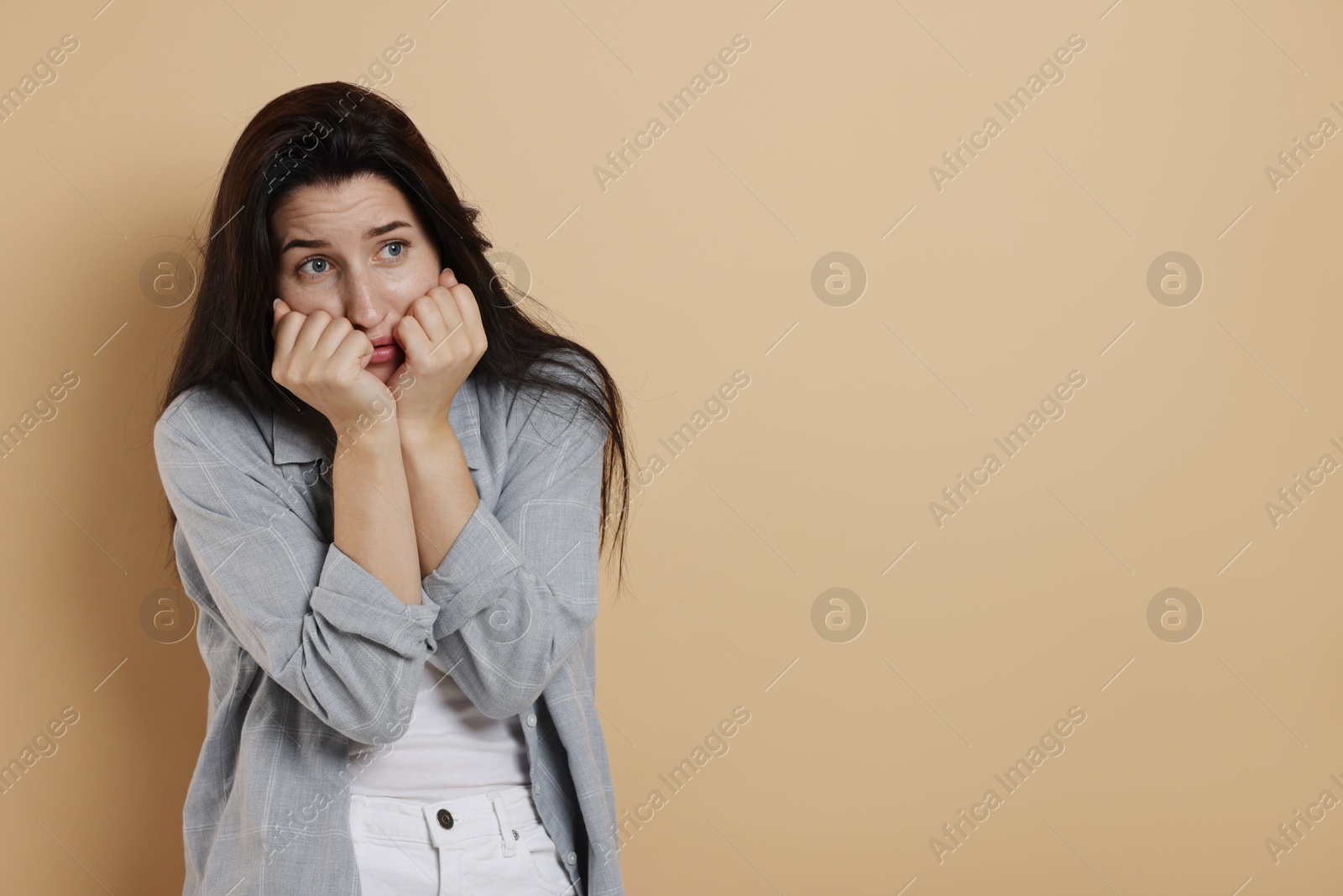 Photo of Worried woman suffering from panic attack on beige background, space for text