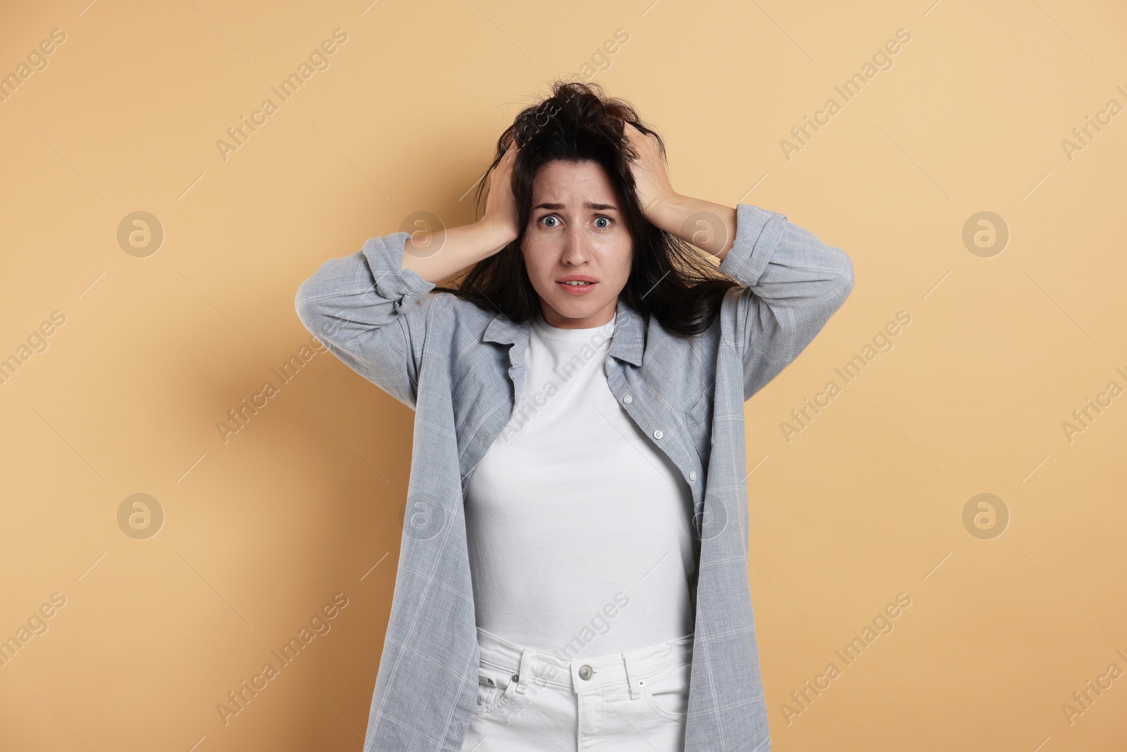 Photo of Worried woman suffering from panic attack on beige background