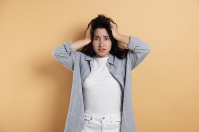 Photo of Worried woman suffering from panic attack on beige background