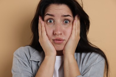 Photo of Worried woman suffering from panic attack on beige background