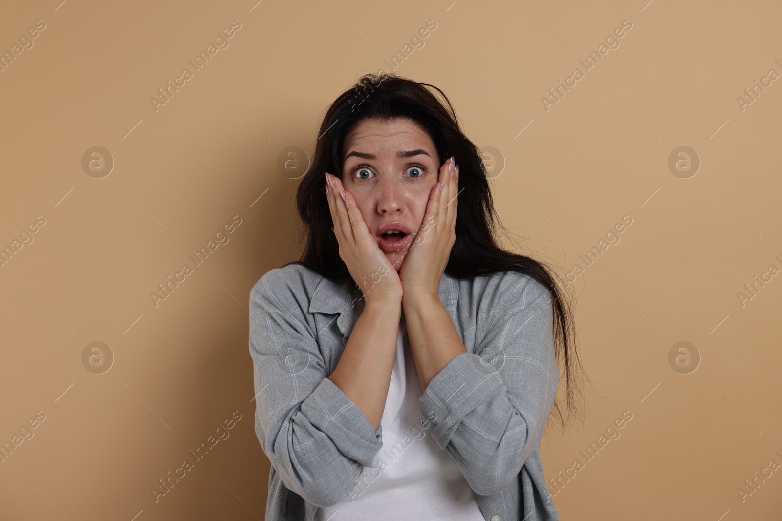 Photo of Worried woman suffering from panic attack on beige background