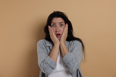 Photo of Worried woman suffering from panic attack on beige background