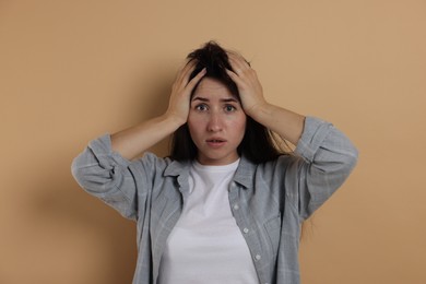 Photo of Worried woman suffering from panic attack on beige background