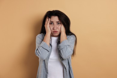 Photo of Worried woman suffering from panic attack on beige background