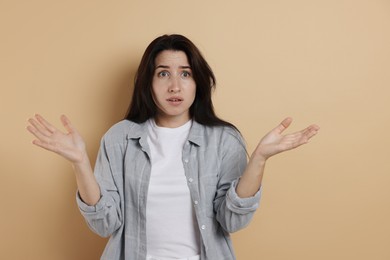 Photo of Worried woman suffering from panic attack on beige background