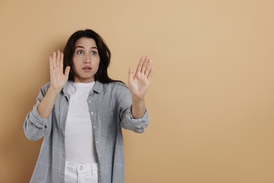 Photo of Worried woman suffering from panic attack on beige background, space for text