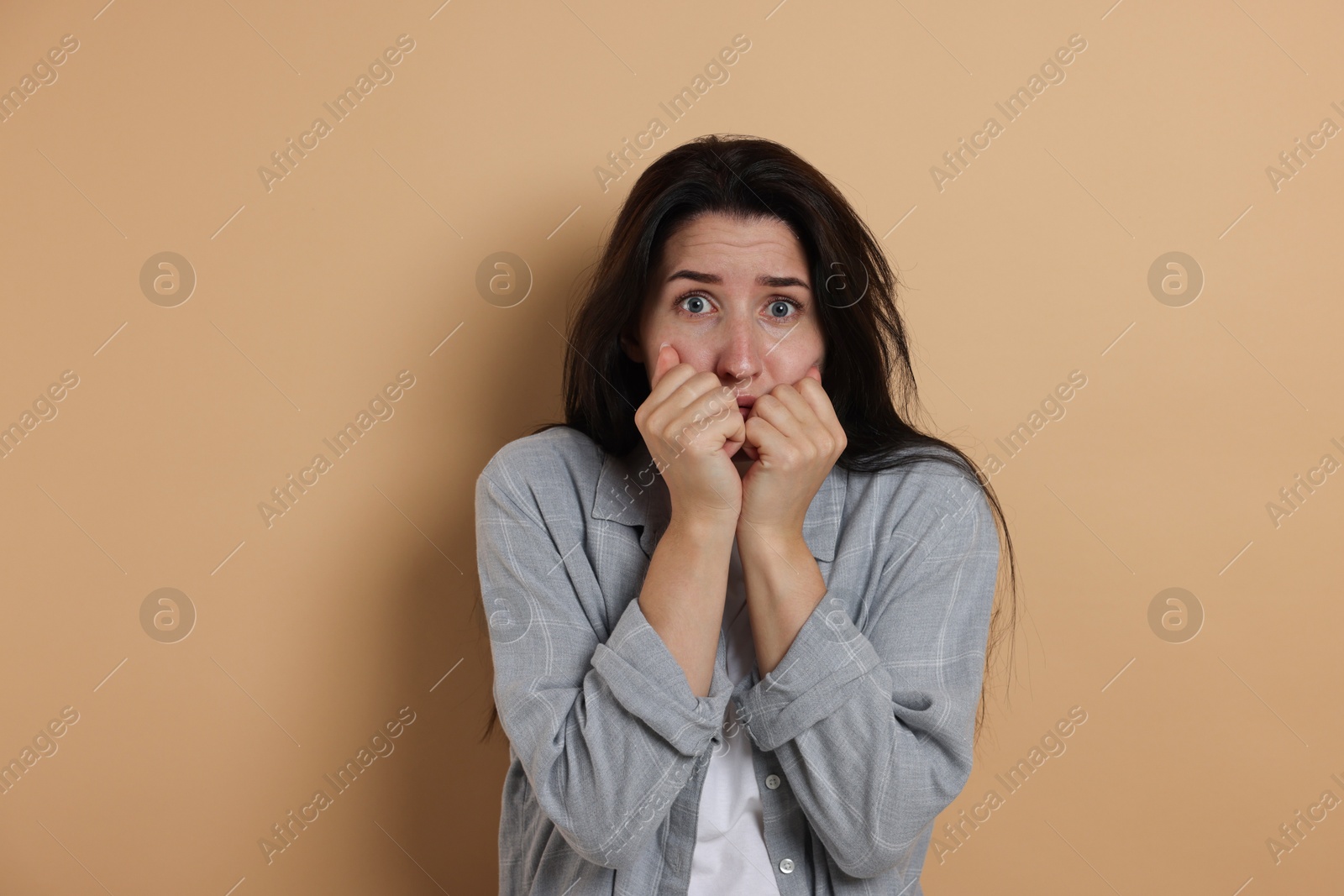 Worried woman suffering from panic attack on beige background Photo of Worried woman suffering from panic attack on beige background