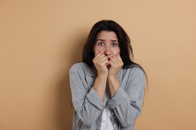 Photo of Worried woman suffering from panic attack on beige background
