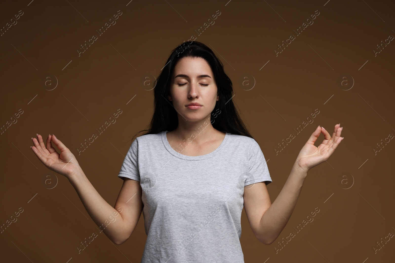 Panic attack. Woman meditating to calm down on brown background Photo of Panic attack. Woman meditating to calm down on brown background
