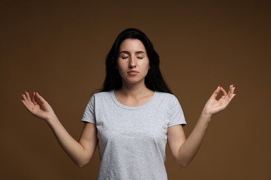 Photo of Panic attack. Woman meditating to calm down on brown background