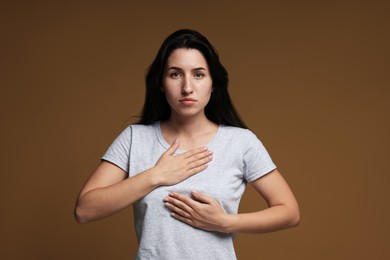 Photo of Panic attack. Woman breathing to calm down on brown background