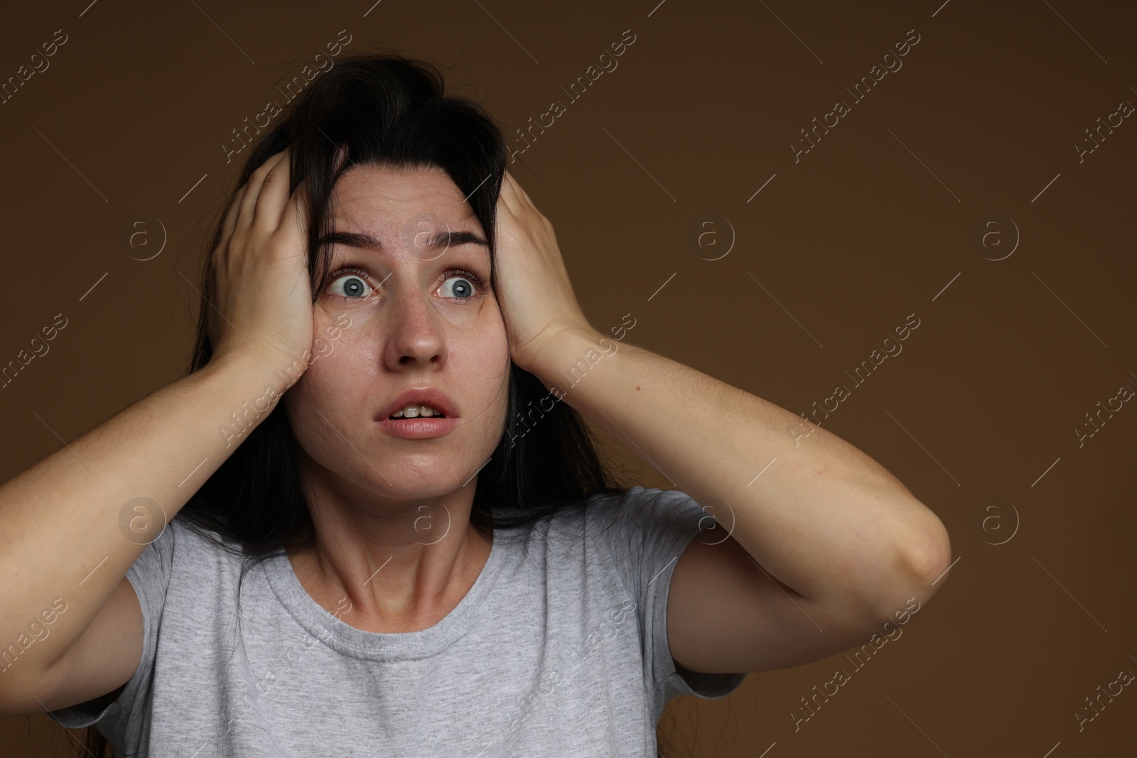 Photo of Worried woman suffering from panic attack on brown background