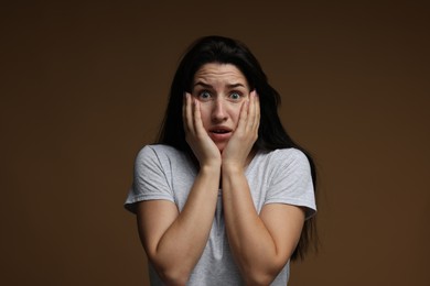 Photo of Worried woman suffering from panic attack on brown background