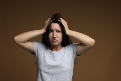 Photo of Worried woman suffering from panic attack on brown background