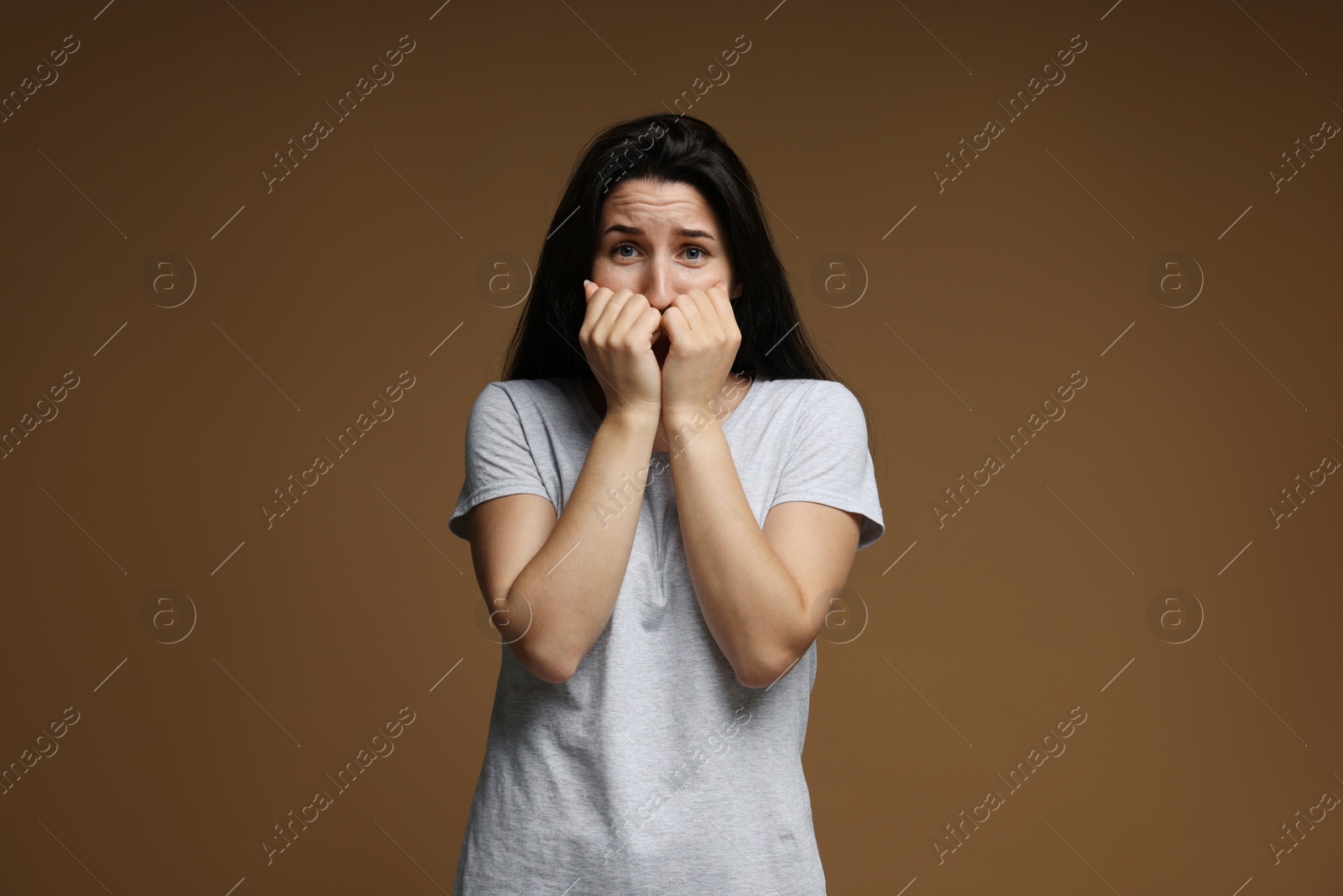 Photo of Worried woman suffering from panic attack on brown background