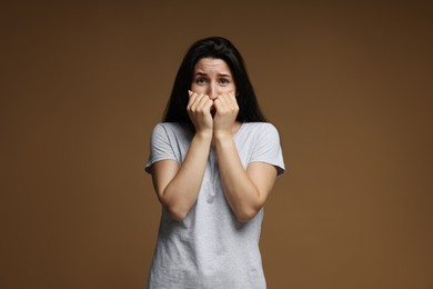 Photo of Worried woman suffering from panic attack on brown background