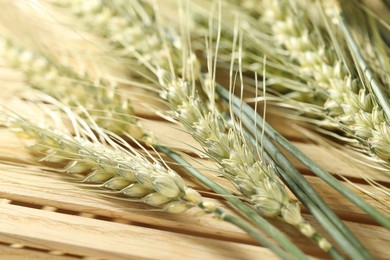 Photo of Green wheat spikes on wooden crate, macro view