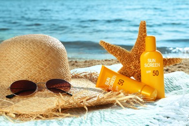 Image of Sun protection. Sunscreens in tube and bottle, hat, sunglasses on beach