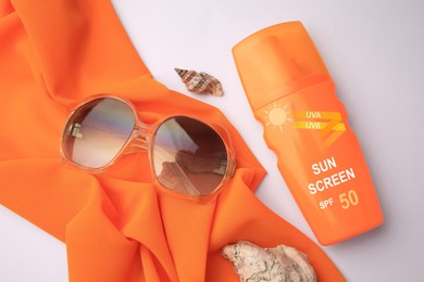 Image of Sunscreen in bottle, sunglasses and cloth on white background, top view. Sun protection product