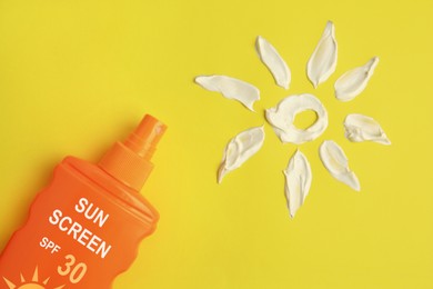 Image of Sunscreen in bottle and sun made of sun protection cream on yellow background, top view
