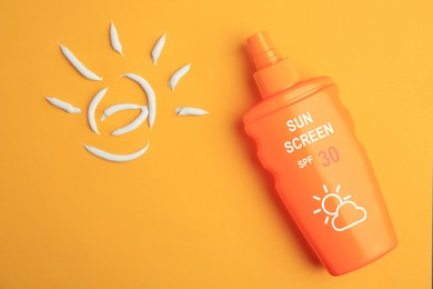 Image of Sunscreen in bottle and sun made of sun protection cream on orange background, top view