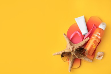 Image of Sunscreens, flip flops and sunglasses on orange background, top view. Sun protection product