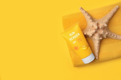 Image of Sunscreen in tube, starfish and beach towel on orange background, top view. Sun protection product