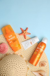 Image of Sunscreens and hat on light blue background, top view. Sun protection product