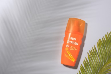 Image of Sunscreen in bottle and green palm leaf on grey background, top view. Sun protection product
