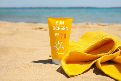 Image of Sunscreen in tube and towel on beach. Sun protection product