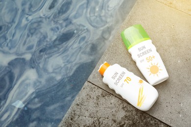Image of Sunscreens in bottles on stone surface near sea, top view. Sun protection product