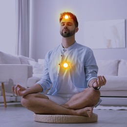 Image of Man meditating in Lotus pose at home. Glowing bubbles representing chakras
