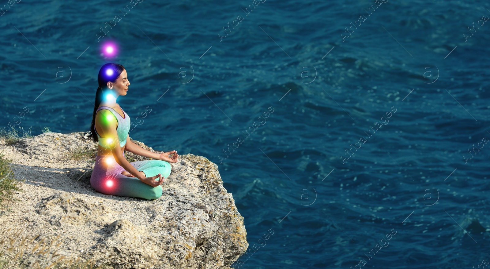 Woman meditating in Lotus pose on cliff near sea. Rainbow lights representing chakras Image of Woman meditating in Lotus pose on cliff near sea. Rainbow lights representing chakras