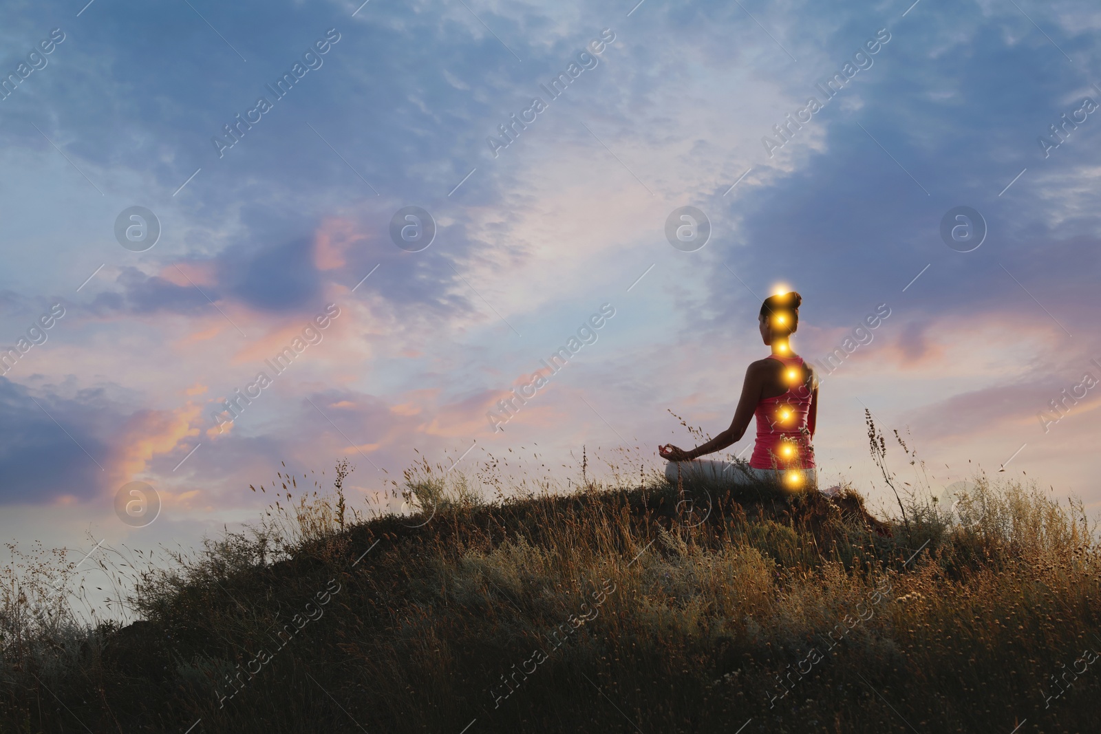 Image of Woman meditating in Lotus pose in nature. Glowing bubbles representing chakras