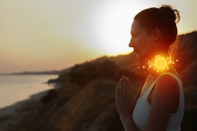 Image of Woman meditating near sea at sunset. Glowing bubble representing chakra