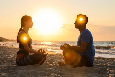 Image of Couple meditating in Lotus pose on beach. Glowing bubbles representing chakras