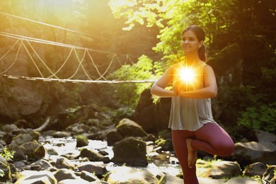 Image of Woman meditating in Tree pose in mountains. Glowing bubble representing chakra