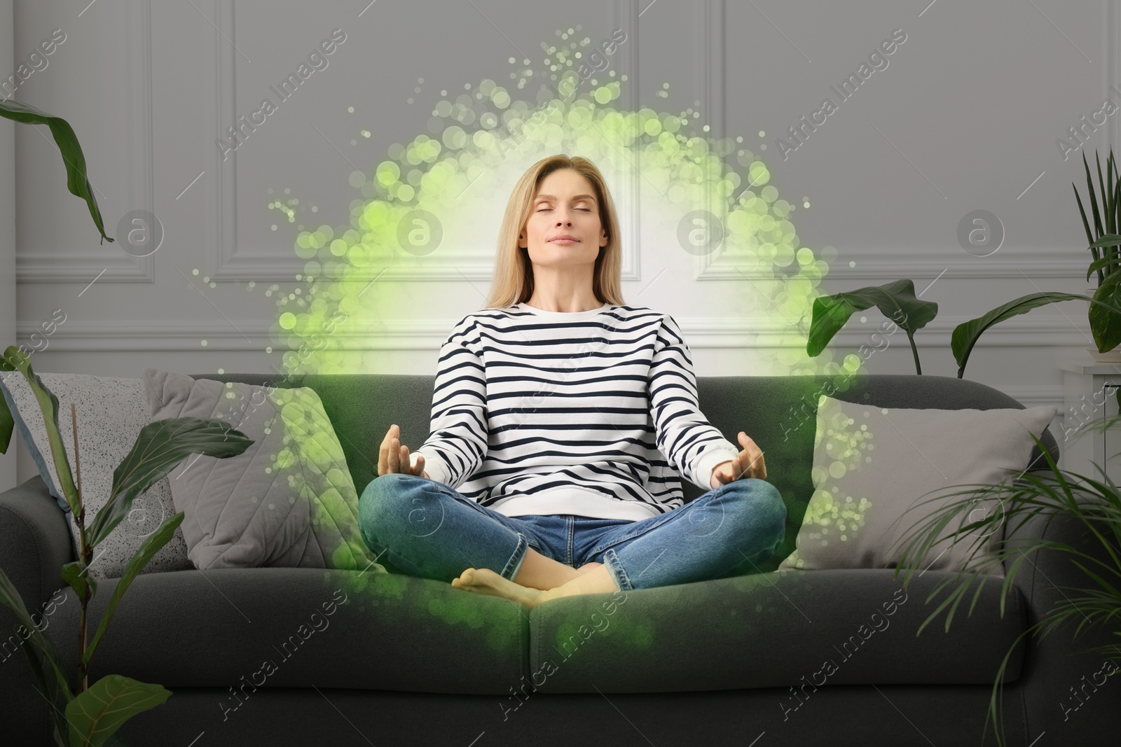 Image of Woman meditating in Lotus pose at home. Bubble around her representing aura
