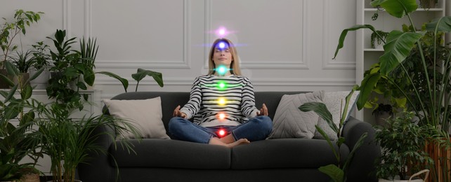 Image of Woman meditating in Lotus pose at home. Rainbow lights representing chakras