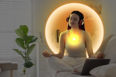 Image of Woman meditating in Lotus pose at home. Glowing bubble around her representing aura