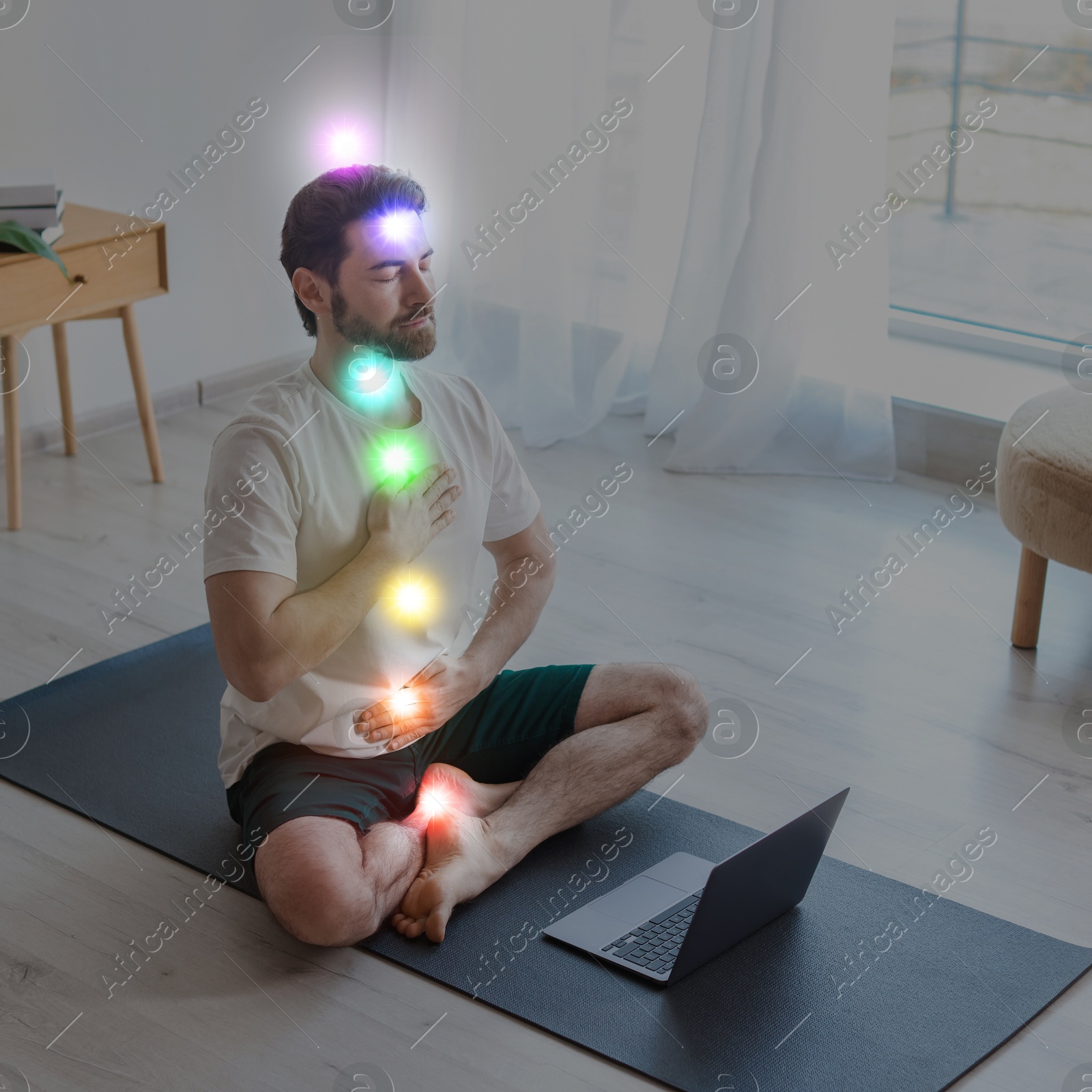 Image of Man meditating in Lotus pose at home. Rainbow lights representing chakras